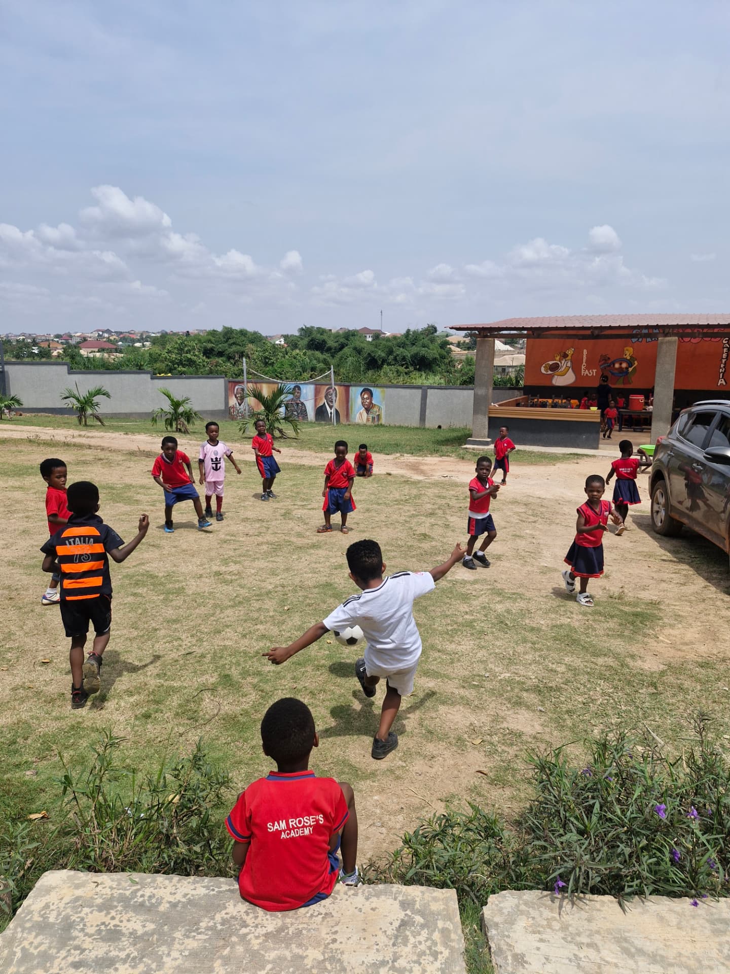 Pupils playing football on the school field beside the cafeteria